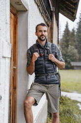 Junger Mann auf einem Bauernhof während einer Wanderung, Vorderriss, Bayern, Deutschland - DIGF08378