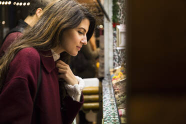 Junge Frau beim Einkaufen auf dem Weihnachtsmarkt - ABZF02564
