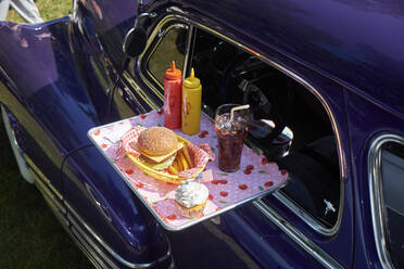 Typisch amerikanisches Fast Food auf einem Tablett an einem Oldtimer, Chevrolet Fleetline - BSCF00609
