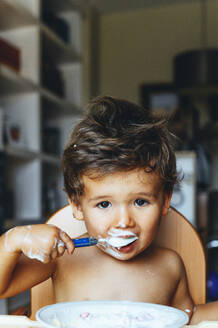 Little boy eating yogurt at home - JCMF00184