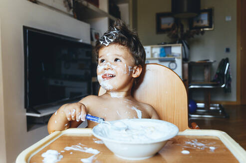 Kleiner Junge sitzt im Hochstuhl und frühstückt zu Hause - JCMF00192