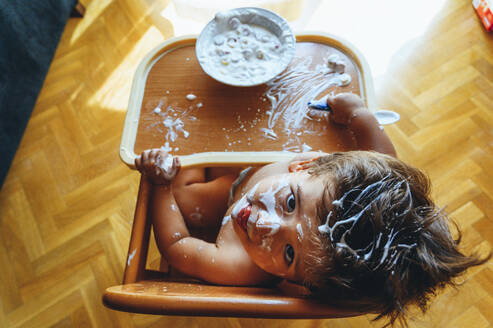 Little boy eating breakfast at home, sitting in high chair, from above - JCMF00194