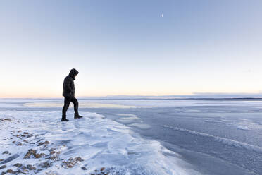 Man walking on frozen Glan lake at sunset in Ostergotland, Sweden - FOLF10936