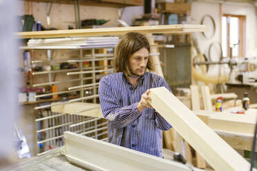 Schreiner hält Holz in der Werkstatt - FOLF10945
