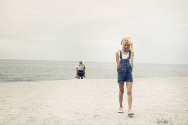 Girl walking in front of her mother and sister on beach - FOLF10952