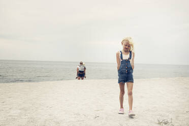 Mädchen geht vor ihrer Mutter und Schwester am Strand spazieren - FOLF10952