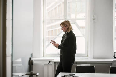 Frau benutzt Smartphone im Büro - FOLF10989