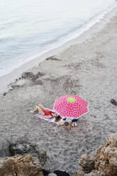 Junge Frau liegt auf einem Handtuch am Strand und nimmt ein Sonnenbad - IGGF01303