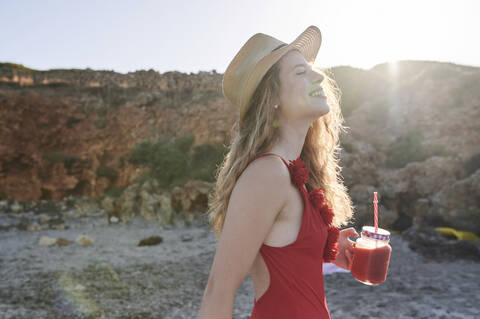 Glückliche junge Frau mit einem Smoothie am Strand, lizenzfreies Stockfoto