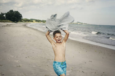 Junge trägt Handtuch am Strand - FOLF11084