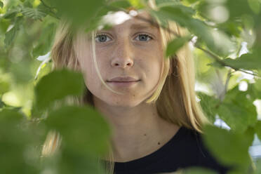 Porträt eines Mädchens im Teenageralter hinter Zweigen - FOLF11150