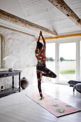 Woman practicing yoga in living room - FOLF11155