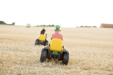 Kinder fahren mit Spielzeugtraktoren auf einem Feld - FOLF11157