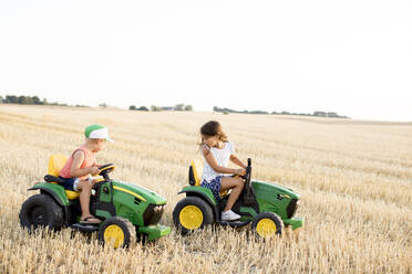 Kinder fahren mit Spielzeugtraktoren auf einem Feld - FOLF11158