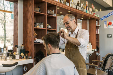 Friseur schneidet einem jungen Mann die Haare - FOLF11244