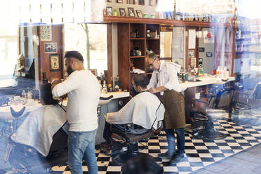 Blick durch das Fenster eines Friseurs, der einem Kunden die Haare schneidet - FOLF11247