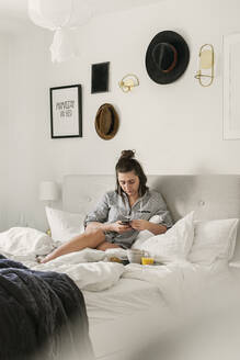 Young woman using smart phone in bed - FOLF11358