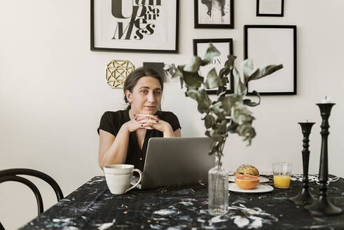 Junge Frau mit Laptop beim Frühstück - FOLF11363