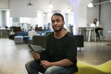 Mid adult man holding laptop on office sofa - FOLF11380