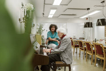 Senior woman playing piano in rest home - FOLF11405