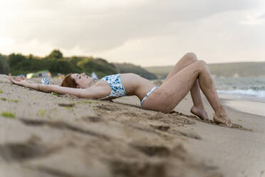 Junge Frau am Strand liegend - AFVF03895