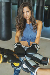 Portrait of woman with boxing gloves with training partners in gym - DLTSF00081
