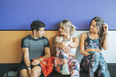 Three athletes having a break and talking in gym - DLTSF00102