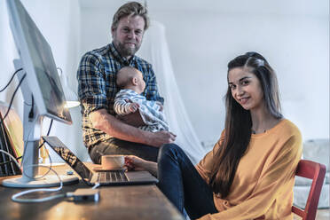 Portrait of young woman with her family in home office - RIBF01000