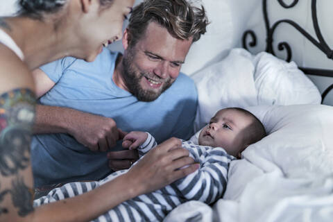 Glückliche Eltern mit ihrem Baby im Bett, lizenzfreies Stockfoto