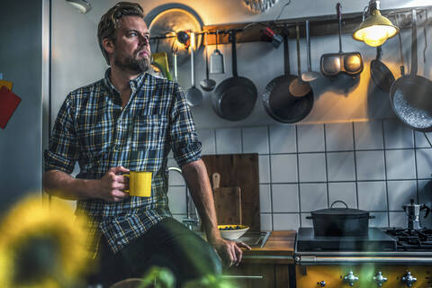 Mann in der Küche zu Hause mit Blick zur Seite, lizenzfreies Stockfoto