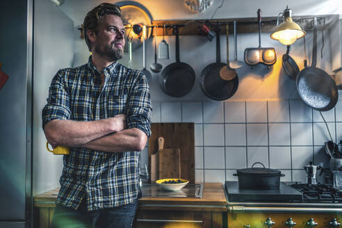 Man in kitchen at home looking sideways - RIBF01061