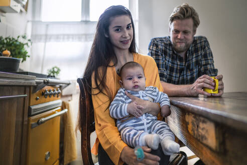 Porträt einer Familie mit Baby am Küchentisch zu Hause - RIBF01069