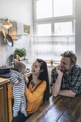 Glückliche Familie mit Baby am Küchentisch zu Hause - RIBF01072