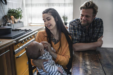 Familie mit Baby sitzt am Küchentisch zu Hause - RIBF01073