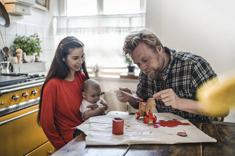 Familie Malerei Holzspielzeug Pferd für Baby am Küchentisch zu Hause, lizenzfreies Stockfoto