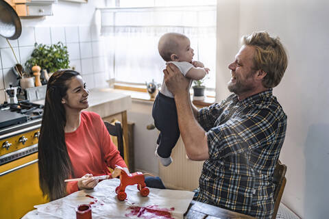 Family lifting up baby at kitchen table at home stock photo