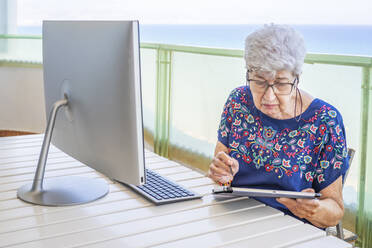 Ältere Frau am Computer auf der Terrasse - DLTSF00107
