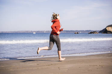 Female jogger at the beach with headphones - UUF19014