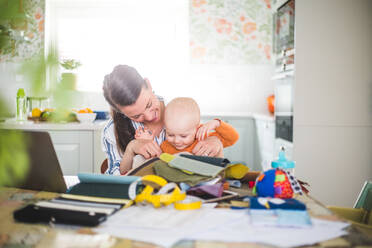 Lächelnde Mutter, die mit ihrer geliebten Tochter spielt, während sie das Arbeitsleben zu Hause ausbalanciert - MASF13473