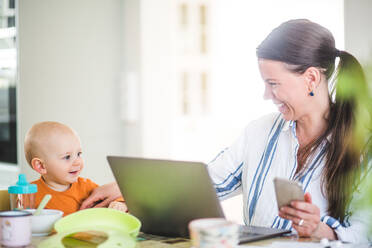 Cheerful businesswoman playing with daughter while running business from home office - MASF13477