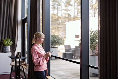 Geschäftsfrau telefoniert am Fenster stehend im Büro, lizenzfreies Stockfoto