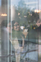 Fröhliche Geschäftsleute im Gespräch im Büro durch Glas gesehen - MASF13523