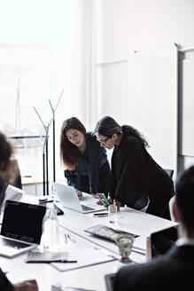 Businesswomen working over laptop at conference table in board room - MASF13547