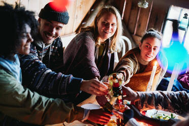 Blick von oben auf einen glücklichen Mann und seine Freunde, die in einer Blockhütte auf Getränke anstoßen - MASF13573