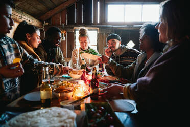 Männliche und weibliche Freunde unterhalten sich beim Essen in einer Hütte am Wochenende - MASF13579