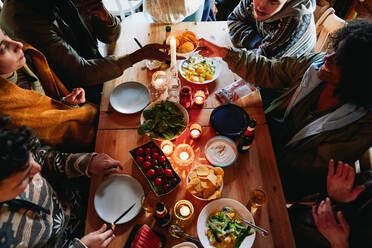 High angle view of friends enjoying food and drink while sitting in log cabin - MASF13583