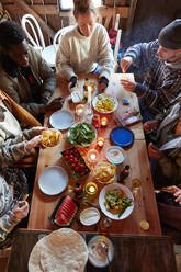 High angle view of friends having food and drink while sitting in cottage - MASF13585