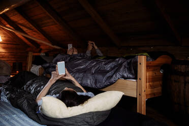Männliche und weibliche Freunde benutzen Mobiltelefone, während sie im Bett liegen - MASF13614