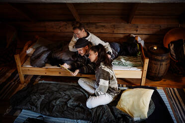 Hohe Winkel Ansicht von Freunden beobachten Film über digitale Tablet beim Entspannen in der Hütte - MASF13620