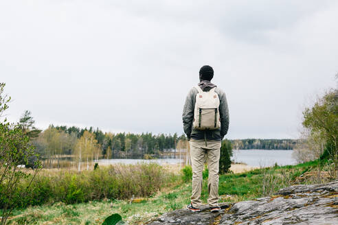 Rückansicht eines Wanderers mit Rucksack, der auf den See blickt, während er gegen den Himmel steht - MASF13635